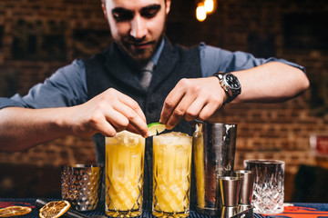 Wall Mural - Professional bartender garnishing with lime cocktails