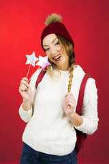 teen girl in white sweater smiling and posing with stars in hand and santa red hat holiday concept