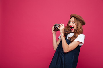 Wall Mural - Young amazed lady with retro camera making photo isolated