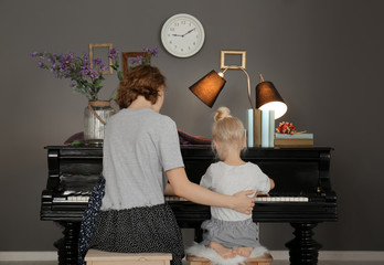 Sticker - Little girl with teacher learning to play piano indoors