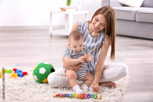 Fototapeta Young mother and cute baby playing on floor at home