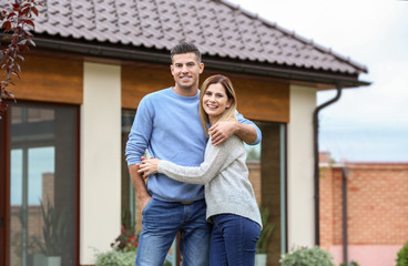 Happy couple standing near their house