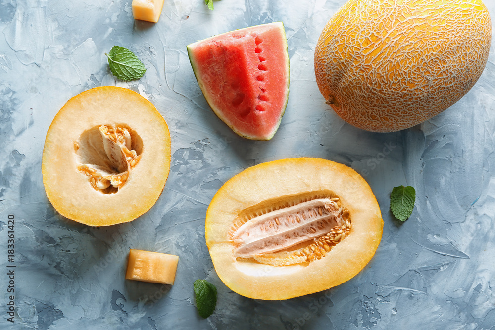 Yummy cut melon and watermelon on grey background, top view