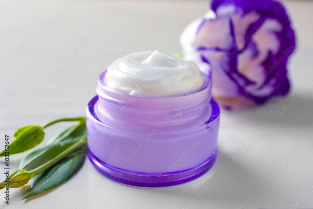 Glass jar with body cream on light background