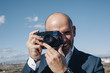 © clementetinin - smiling photographer man in blue suit working with his photo camera