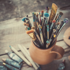 Poster - Paintbrushes in a jug from potters clay, wooden palette and paint tubes.