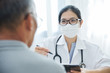 © eggeeggjiew - Asian Female Doctor talking to senior man patient.