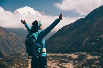 Wall Mural - standing young woman with backpack and raised up arms on the hill and looking on mountains. landscap