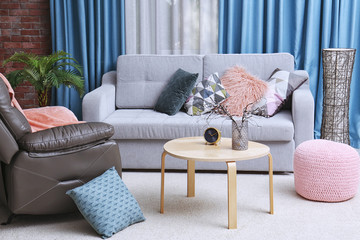 Living room interior with grey sofa and leather armchair