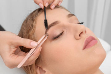 Young woman having eyebrow correction procedure in beauty salon