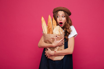 Wall Mural - Shocked woman looking at baguettes with opened mouth isolated