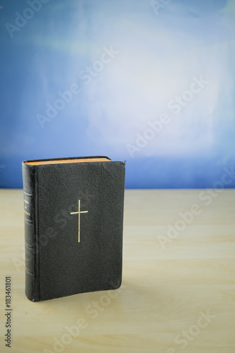 Fotografia, Obraz Ein kirchliches Gesangbuch auf einem Holztisch, dahinter blauer Himmel, Textfrei