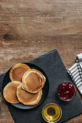 Wall Mural - top view of delicious pancakes with maple syrup and jam on wooden table