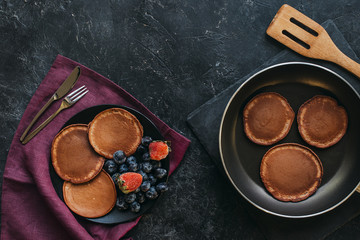 Wall Mural - top view of fresh pancakes on plate and frying pan on black tabletop