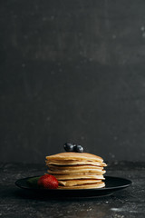 Wall Mural - plate of delicious pancakes with berries on black concrete surface