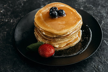 Wall Mural - stack of freshly backed pancakes with berries on black table