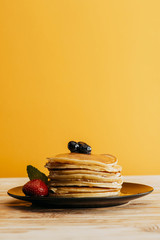 Wall Mural - stack of delicious pancakes with berries on yellow