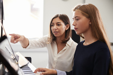 Wall Mural - Female Pupil With Teacher Playing Piano In Music Lesson