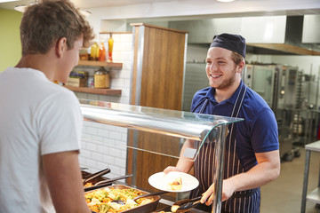 Teenage Students Being Served Meal In School Canteen