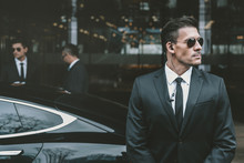 Bodyguard Standing At Businessman Car And Reviewing Territory