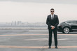 © LIGHTFIELD STUDIOS - serious bodyguard standing with sunglasses and security earpiece on helipad and looking at camera