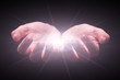 Woman hands cupped protecting and holding bright, glowing, radiant, shining light. Emitting rays or beams expanding. Religion, divine, heavenly, celestial concept. Black background, front view