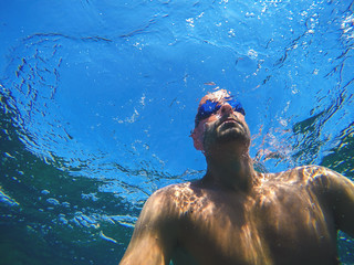 Wall Mural - Underwater photo of a young man swimming in the turquoise exotic sea for summer vacation.