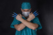 Surgeon in scrubs with syringes arms crossed on a black background