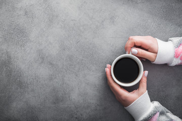 woman in warm sweater holds a white cup of coffee