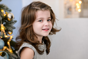 Merry Christmas celebration. Beautiful little girl in a amazing dress near the Christmas tree. Christmas miracles. Happy New Year