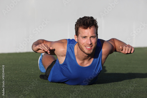Fotomural Fitness training back fat exercise fit man doing superman variation of lower body workout