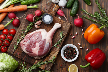 Raw goose leg and fresh vegetables