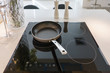 Frying pan on modern black induction stove, cooker, hob or built in cooktop with ceramic top in white kitchen interior