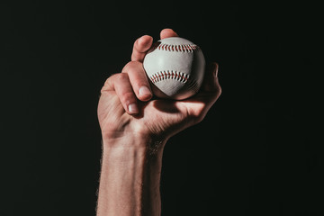 partial view of sportsman holding baseball ball isolated on black