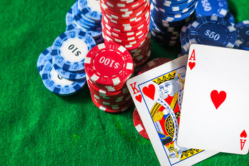 Poker chips with two cards king and ACE on a green background.