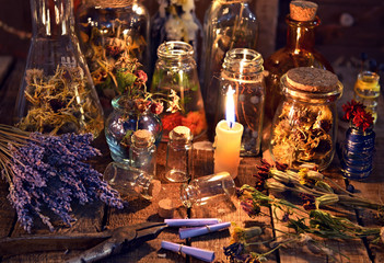 Bottles with herbs, lavender flowers, paper scrolls and magic objects on witch table. Occult, esoteric, divination and wicca concept. Mystic, old apothecary and vintage background