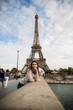 © Aleksandr - Beautiful girl posing to the photographer against the background of the Eiffel Tower. Autumn photosession. Sunny weather. Beautiful smile and makeup