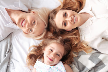 Wall Mural - Family unity. Happy delighted positive family looking at you and smiling while lying together