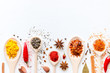 Spoons with condiments and spices on a white background with space for text