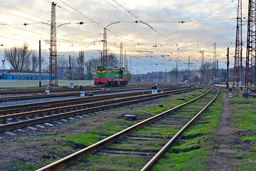 Railway station against beautiful sky at sunset. Industrial landscape with railroad, colorful cloudy blue sky. Railway sleepers. Railway junction. Heavy industry. Cargo shipping. Travel background