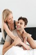 © Drobot Dean - Pretty couple of smiling man and woman sitting in bed