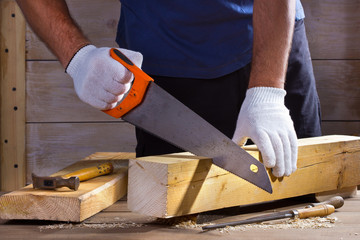 Wall Mural - Man hand with saw cutting wooden boards