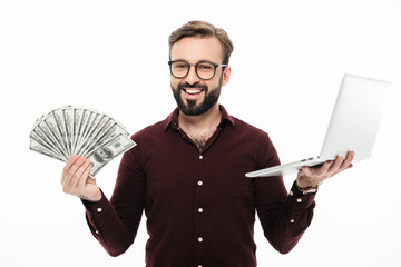 Wall Mural - Cheerful young man holding money and laptop computer.