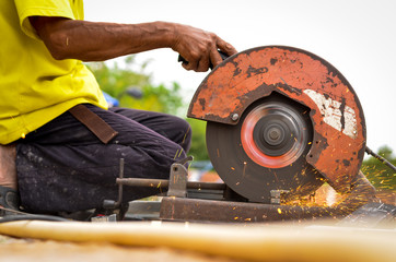 The man use cutting metal with disc grinder abrasive saw producing bright colorful sparks. Worker cuts metal with hand electric tool.