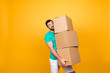 © deagreez - Concept of courier and messenger service. Grimacing handsome guy is trying to keep big stack of cardboard bosex in his hand, isolated on yellow background