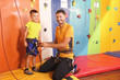 © Africa Studio - Trainer helping little boy to put on gear in climbing gym