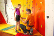 © Africa Studio - Trainer helping little girl to put on gear in climbing gym