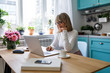 © LUMINA IMAGES - Beautiful senior Caucasian woman reading on her laptop and sitting at home  kitchen.