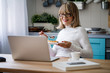 © LUMINA IMAGES - Pretty senior Caucasian woman eating dessert and reading on laptop at her home.