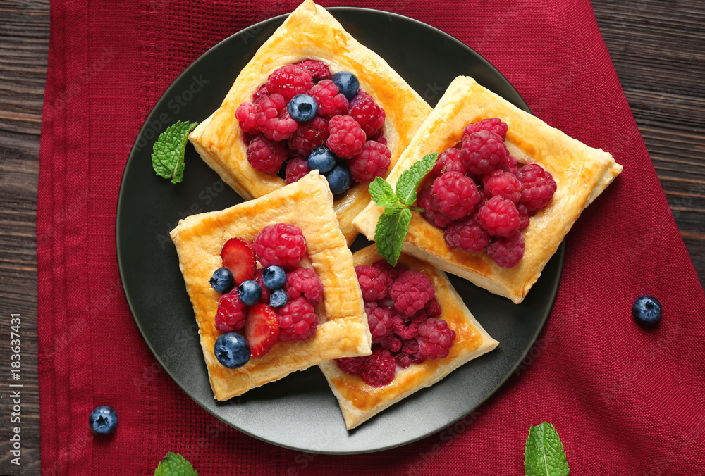 Plate with yummy berry puff pastry on wooden table